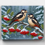 Two birds perched on a branch with red berries and snowflakes in the background