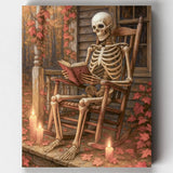Halloween paint by numbers kit featuring a skeleton reading in a rocking chair by candlelight with autumn leaves.
