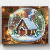 Christmas-themed snow globe with a log cabin inside, surrounded by festive decorations.
